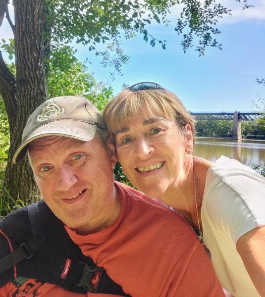 Sarah and Simon with their heads together in front of a tree