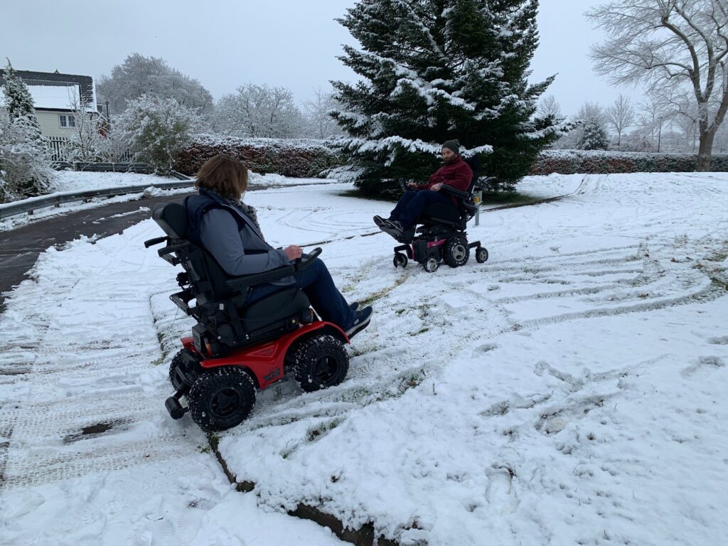 all terrain wheelchair being driven up a snowy slope