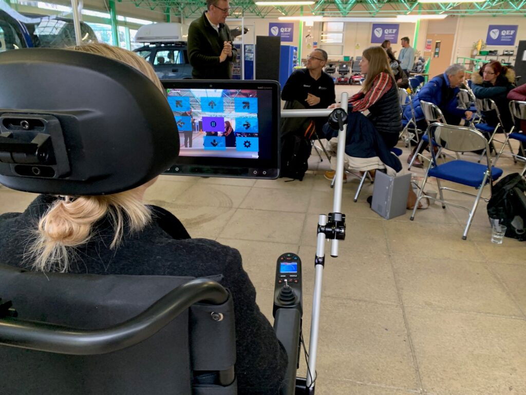 a person sitting in a powered wheelchair looking at a control screen for the wheelchair