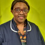 Gertrude in her nurses uniform against a green background