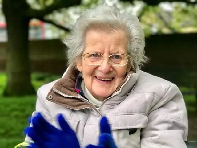 Elisabeth smiling and clapping her hands wearing blue gloves
