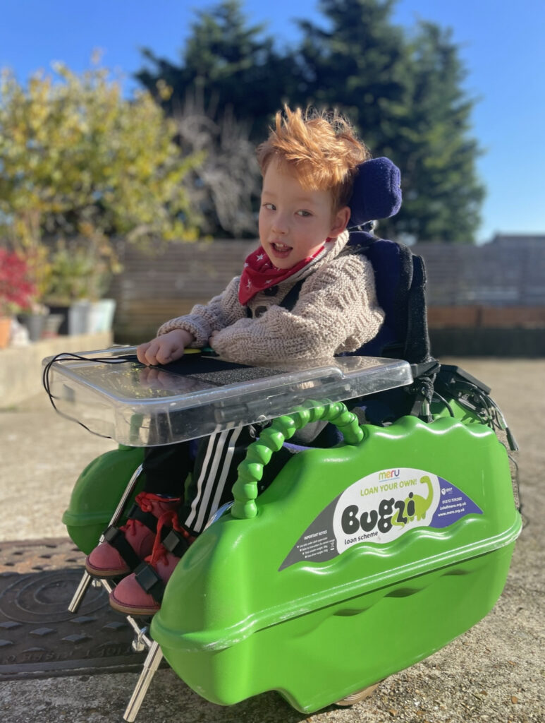 Young boy in bright green bugzi powered wheelchair